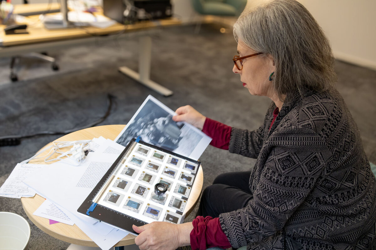 Althea Greenan in her office, working with slides and a print of artworks