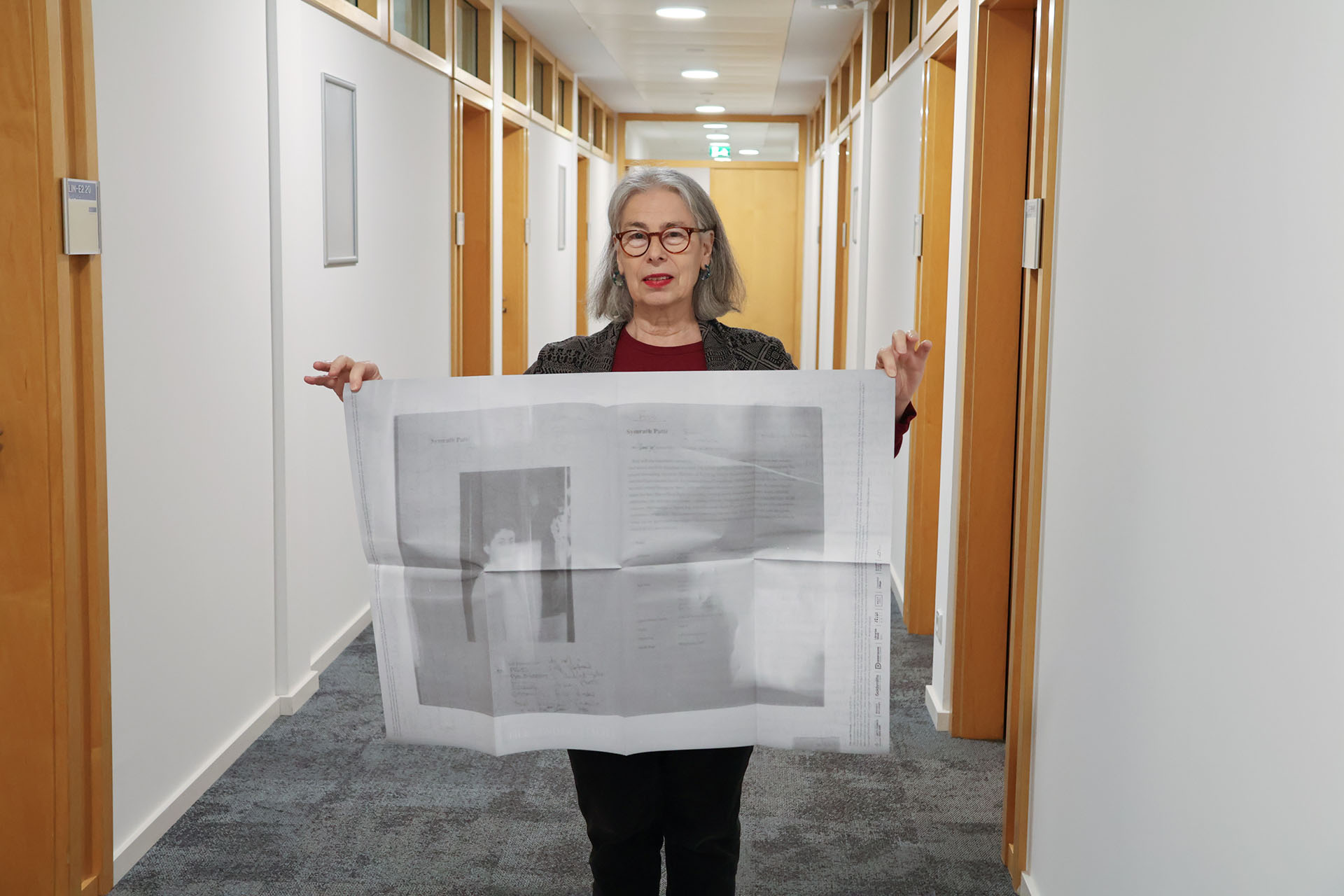Althea Greenan holding up a print of an artwork from the archive