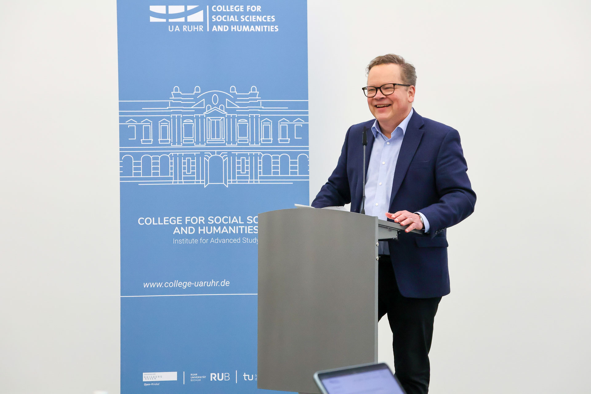 photo of William Donahue smiling while standing behind speaker's desk