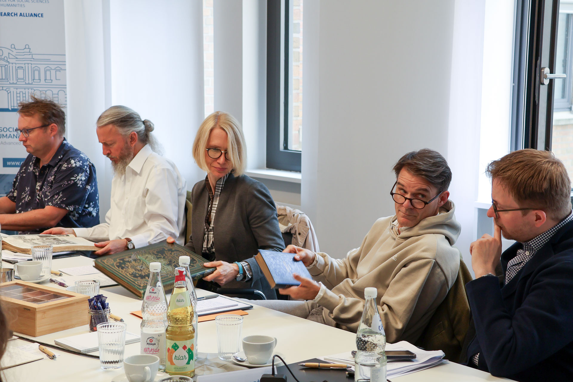 photo from the workshop 'Editing Journal Literature', participants sitting around a table, one handing over a book