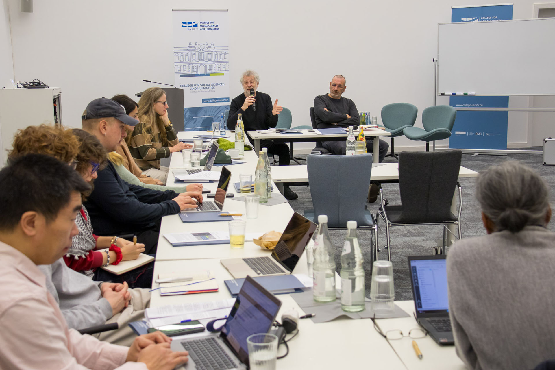 photo from the workshop, Prof. Feierstein speaking, participants sitting at tables