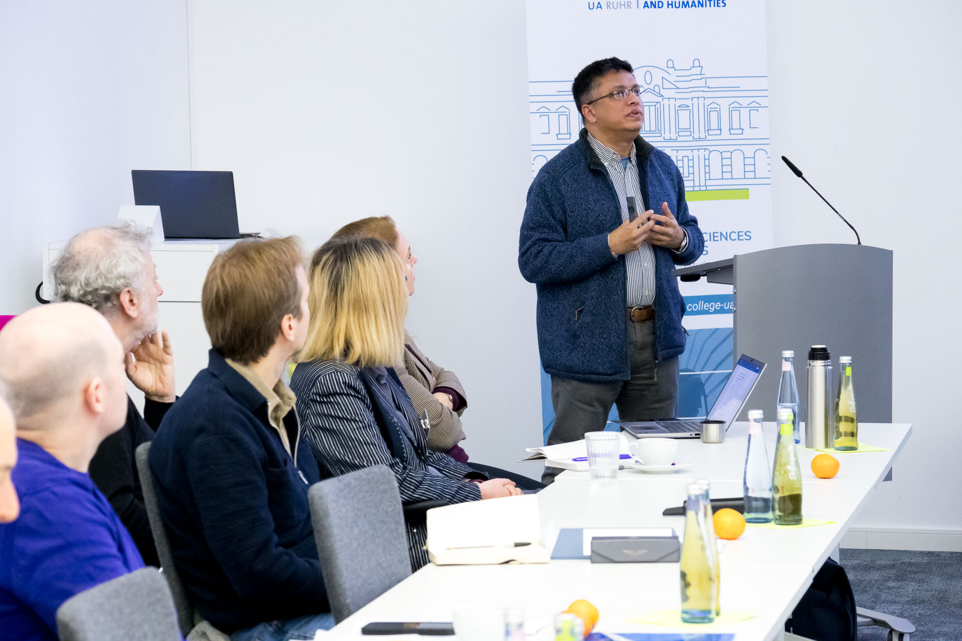 photo from the workshop 'Perpetrator Memory in Spanish culture', participants sitting at a table, a speaker presenting