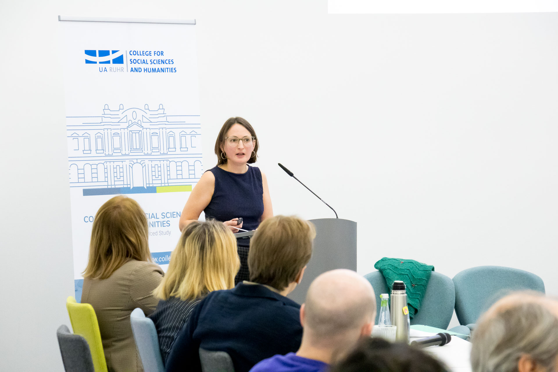photo from the workshop 'Perpetrator Memory in Spanish culture', participants sitting at a table, a speaker presenting