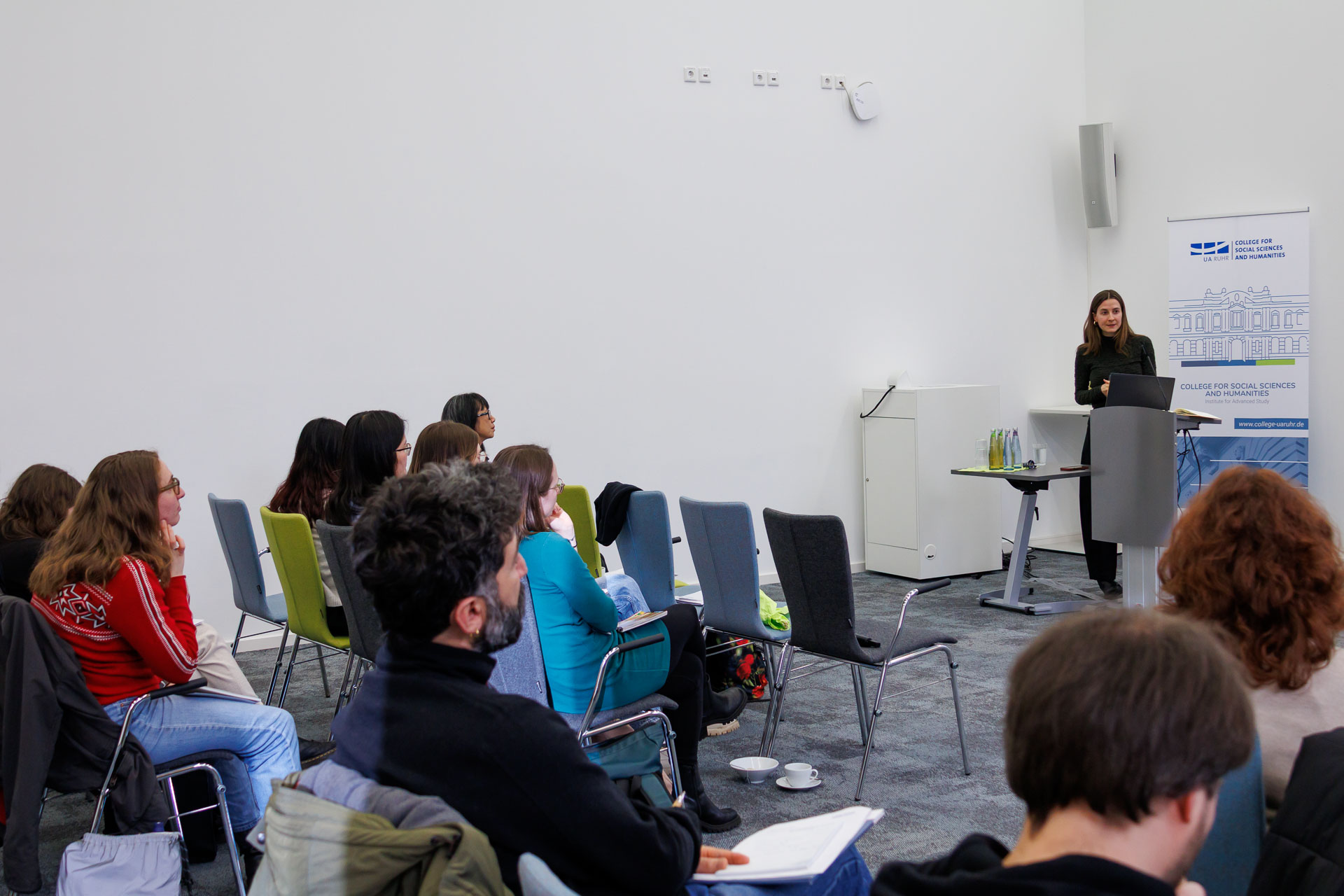 photo from the workshop 'Ethnic-Racial Socialisation', a speaker standing at a speaker's desk, several persons sitting in the foreground