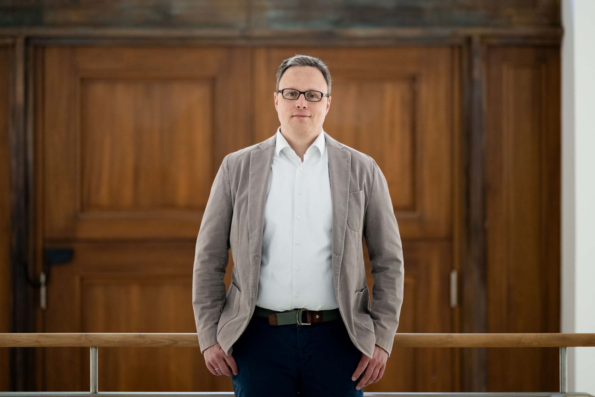 Matthias Kranke leaning against a bannister infront of a large wooden door