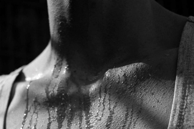 black and white photo: close-up of a person's chest with sweat droplets